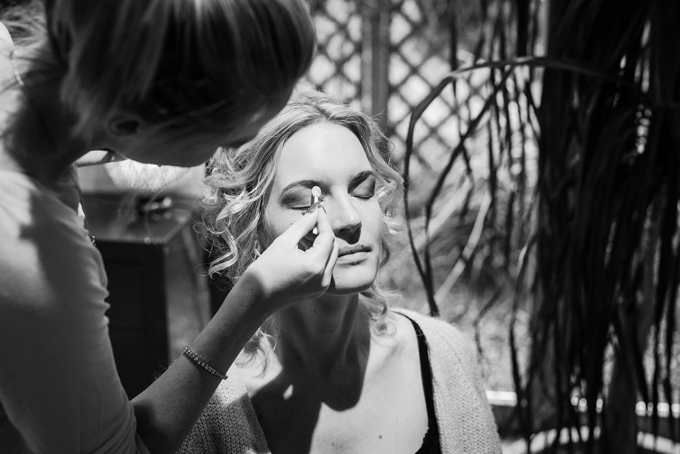 Schwarzweißfoto: Braut bekommt vor der Hochzeit die Augen geschminkt