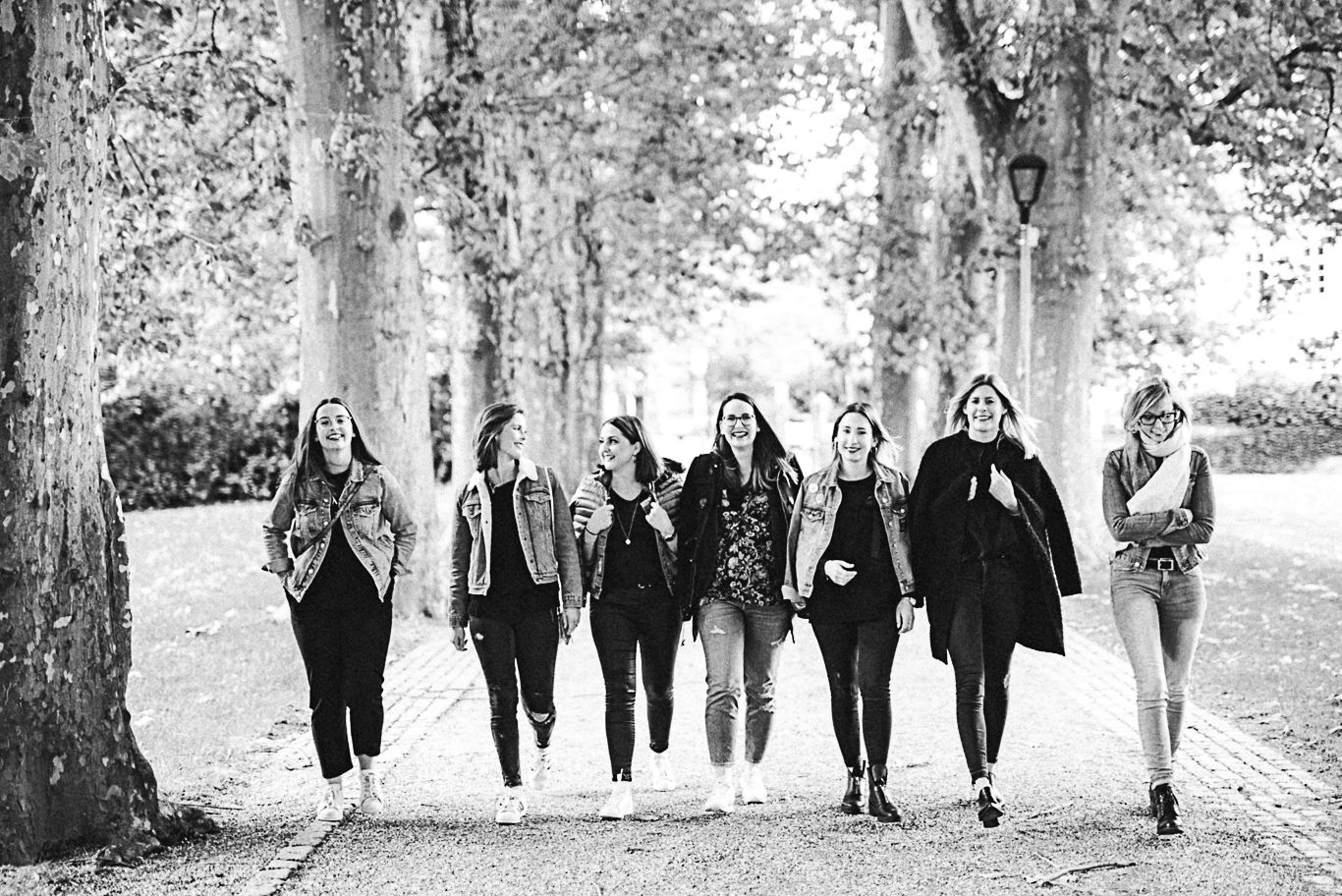 Gruppe Frauen geht lachend eine Allee entlang, Schwarzweißaufnahme