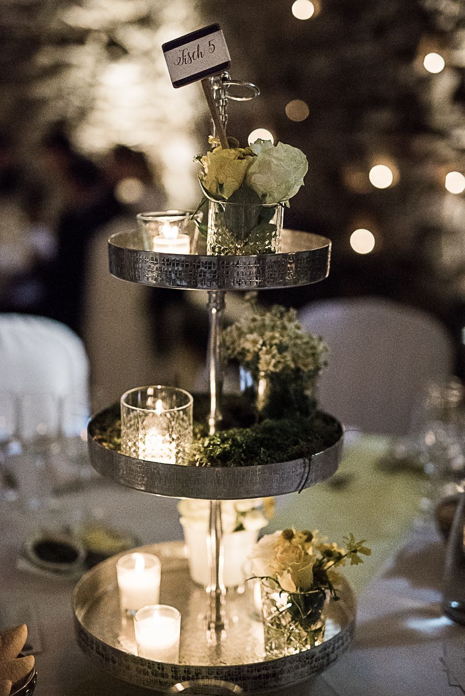 Etagere mit Kerzen und Blumen steht auf der Tafel im Abendlicht