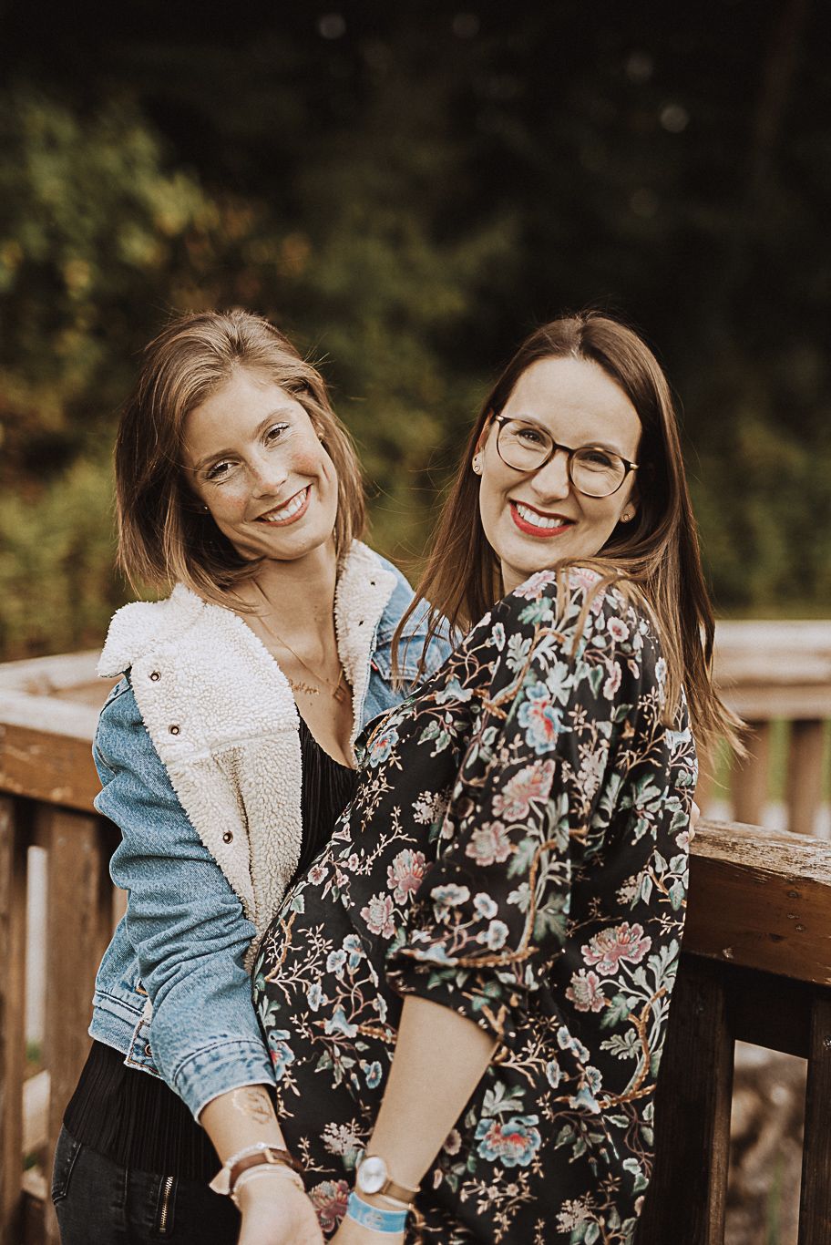 Zwei Frauen mit Brille lächeln eng aneinander gelehnt