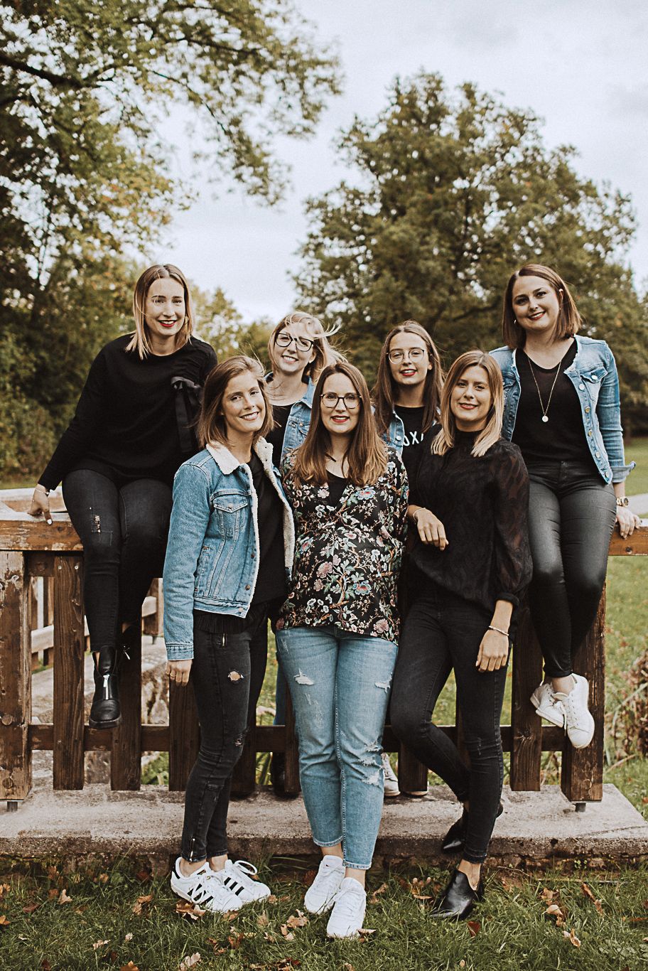 Gruppe von Freundinnen steht lachend auf einer Holzbrücke
