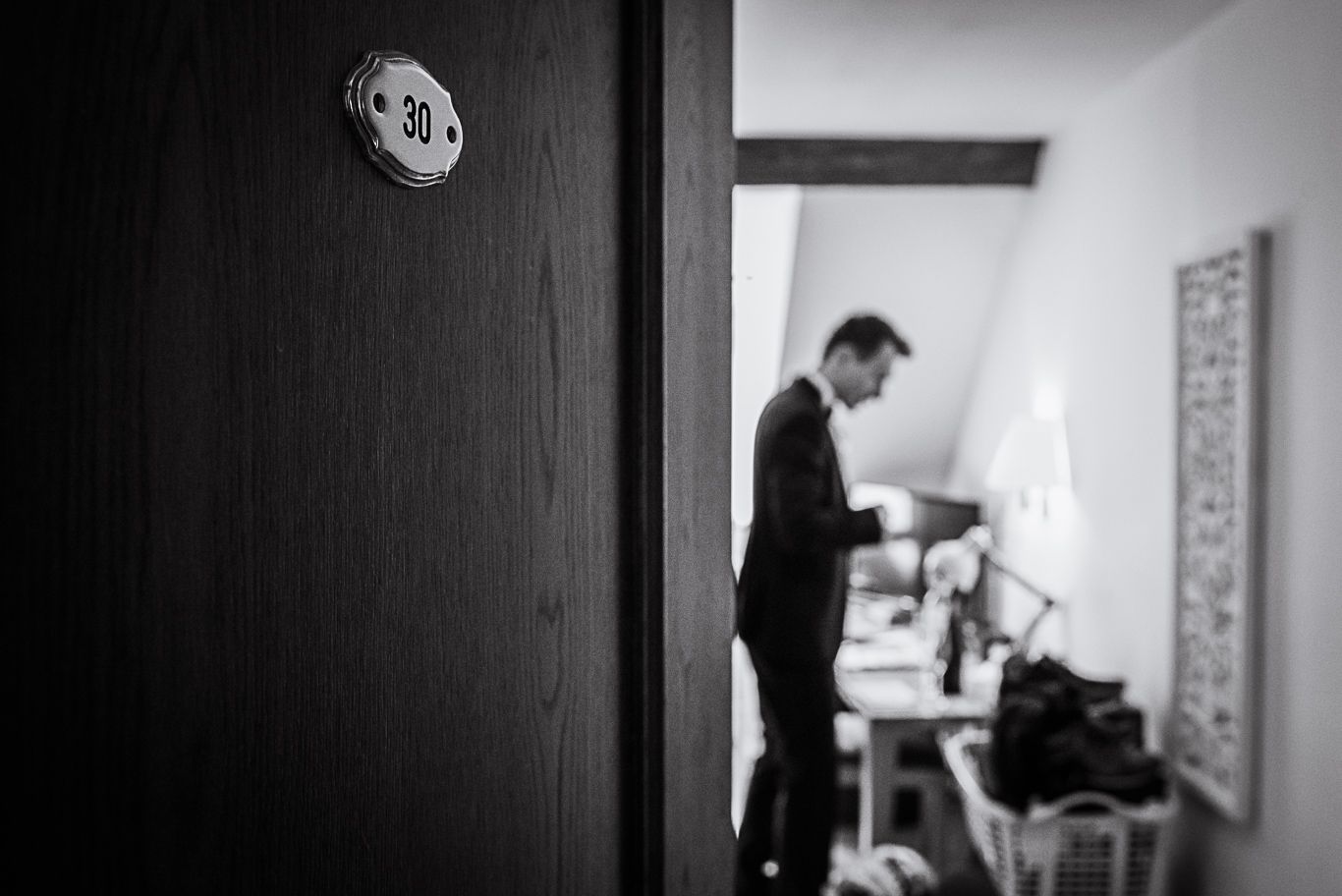 Bräutigam steht allein am Fenster eines Hotelzimmers, Schwarzweißaufnahme