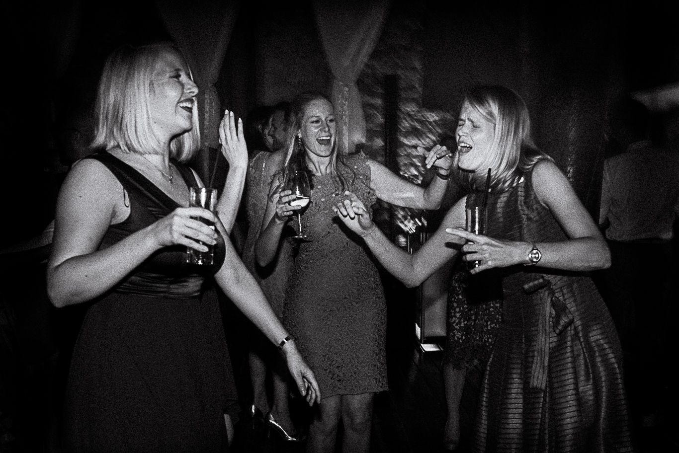 Schwarzweißaufnahme, drei Frauen lachen mit Sektgläsern in der Hand