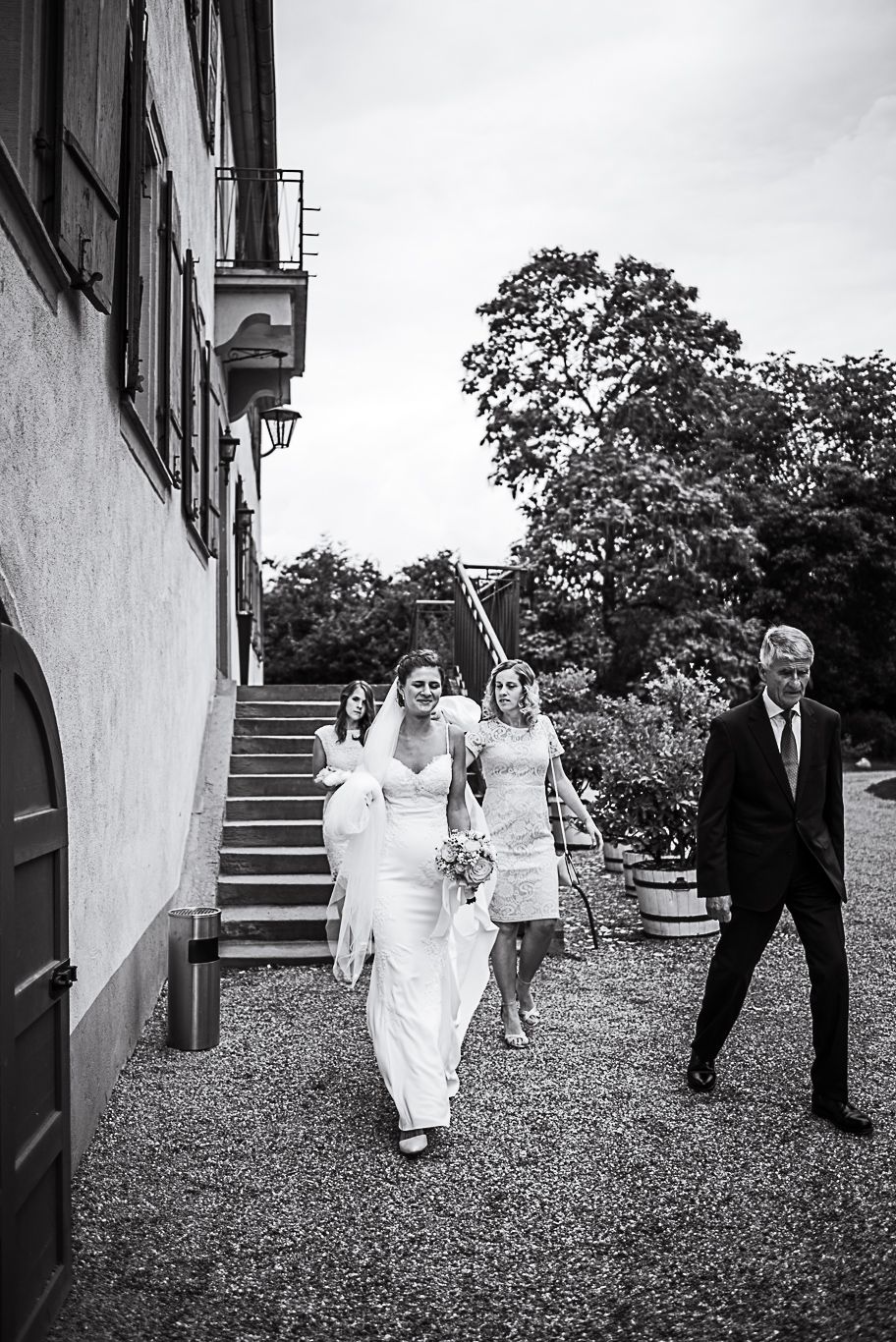 Schwarzweißaufnahme der Braut, die mit dem Vater zum Schloss geht