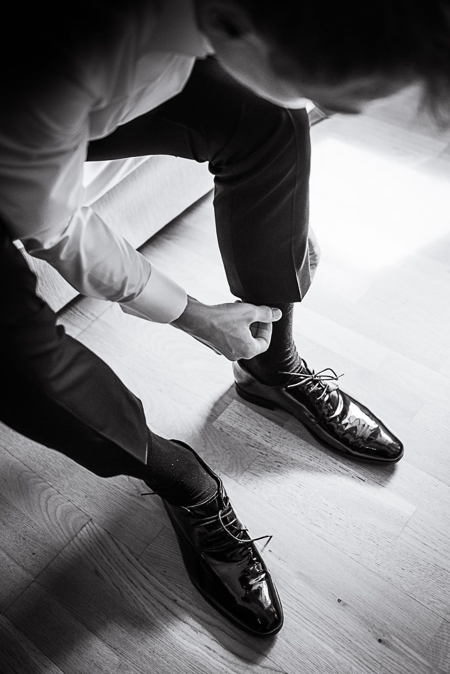 Bräutigam zieht sich schwarze Socken über die Füße, Schwarzweißaufnahme