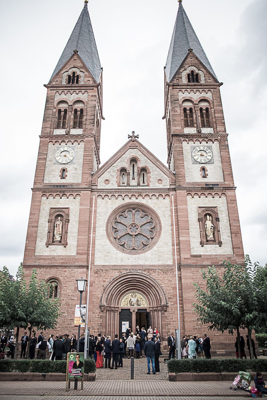 Backsteinkirche mit zwei Türmen vor wartenden Hochzeitsgästen