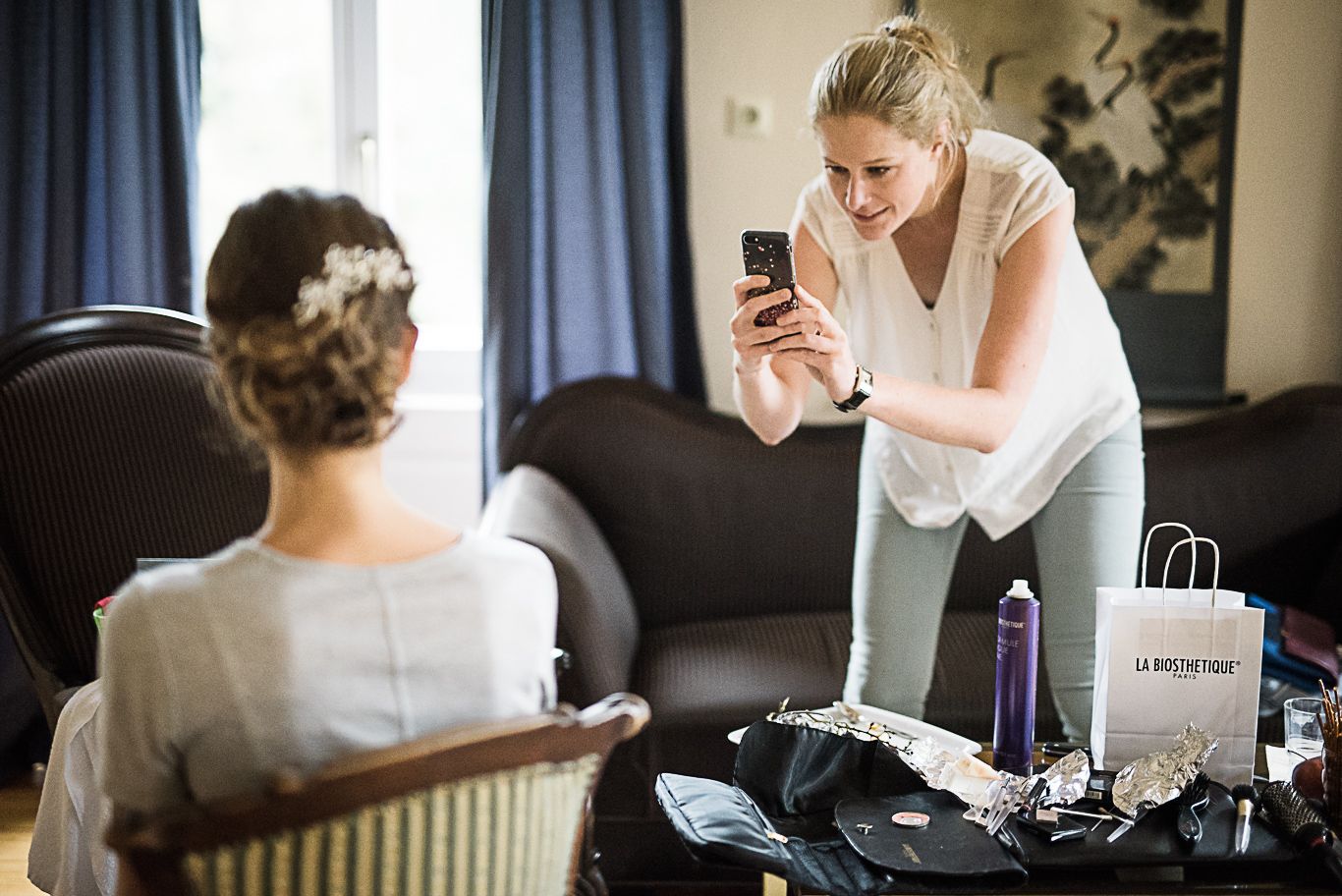 Freundin fotografiert die Braut mit dem Smartphone beim Styling