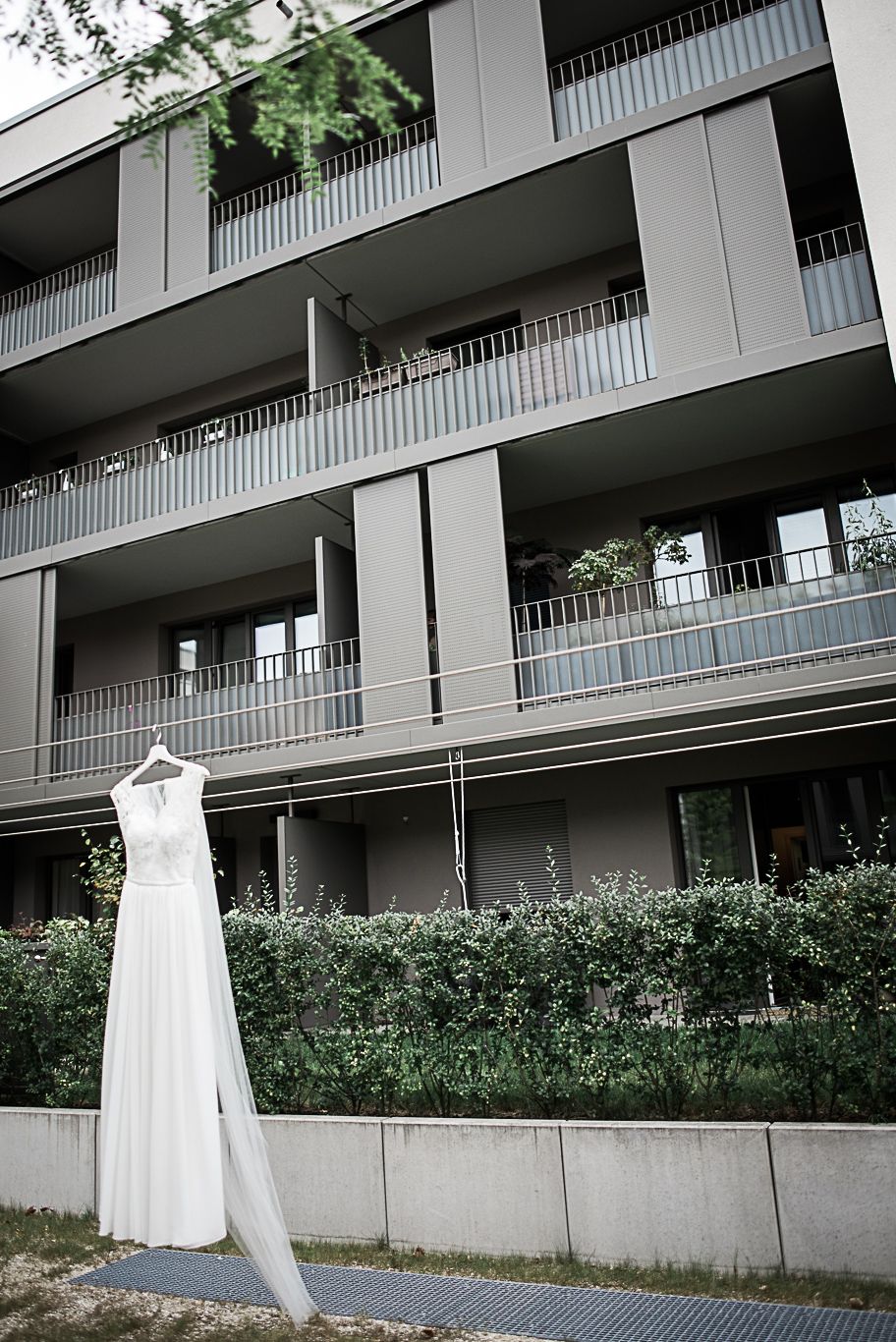 Brautkleid hängt an einem Balkon eines modernen Wohnhauses