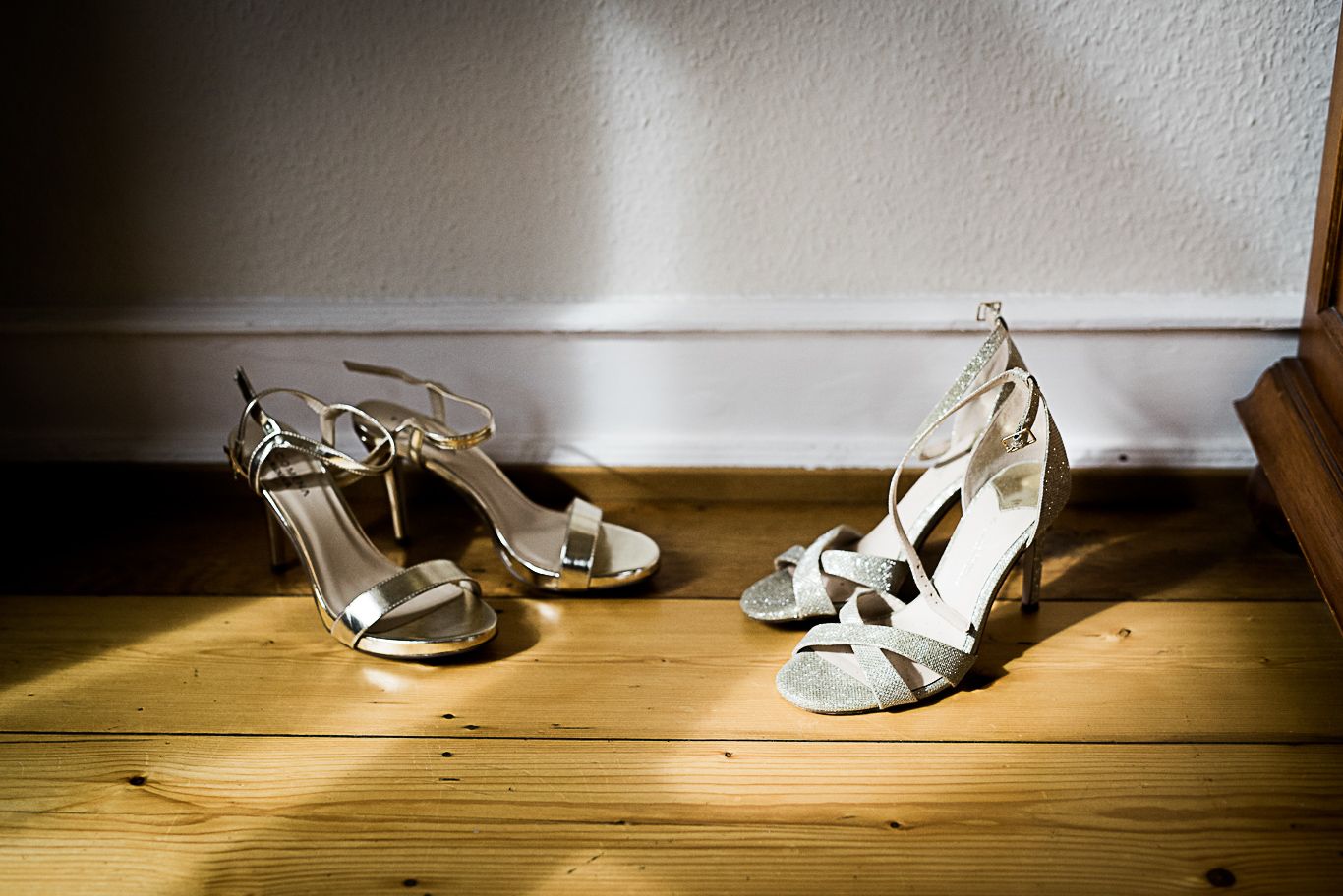Brautschuhe stehen auf einem Holzboden vor weißer Wand