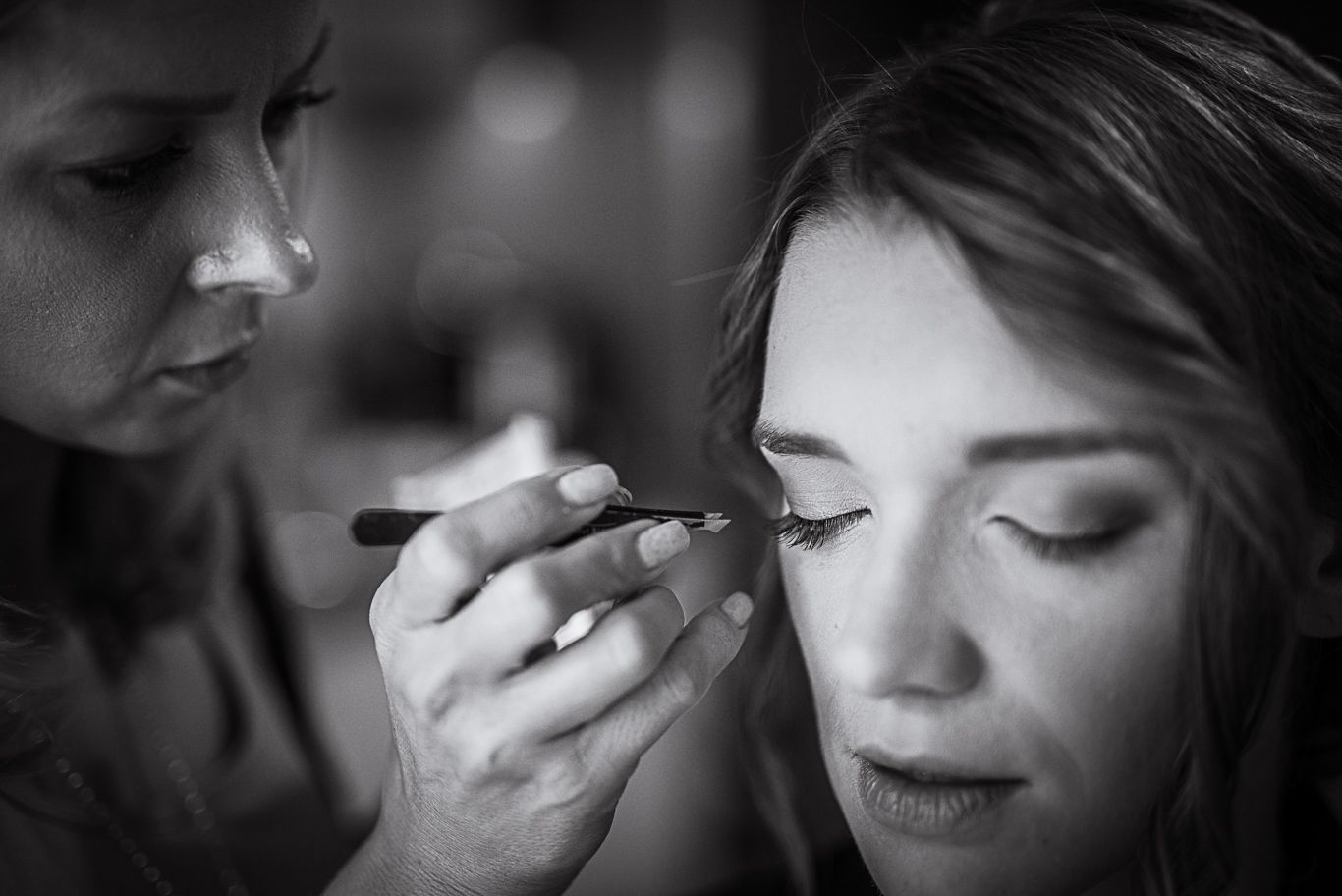 Schwarzweißaufnahme der Braut, der die Wimpern getuscht werden