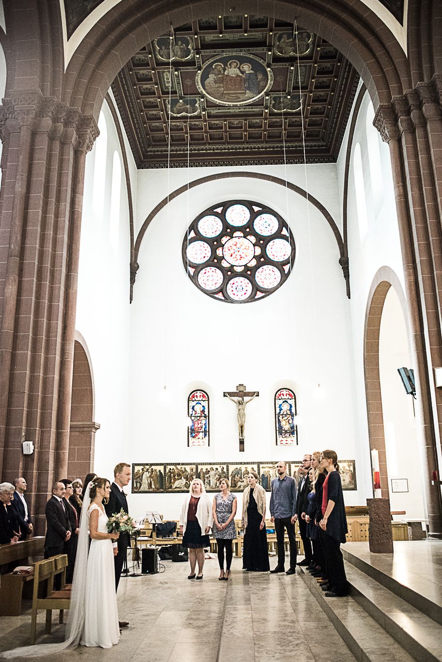 Brautpaar steht vor dem Altar unter einem Kirchenfenster