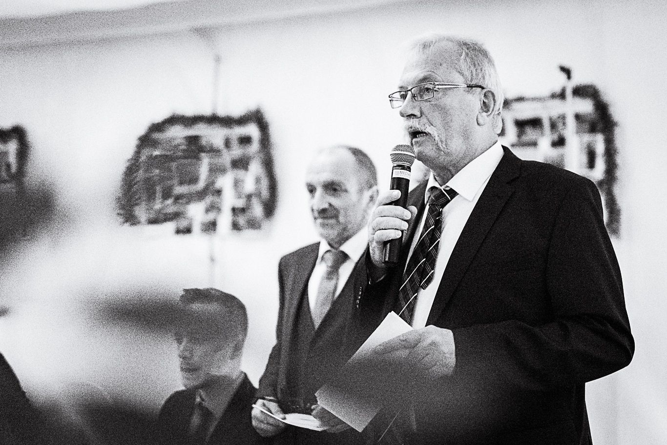 Älterer Gast hält Rede mit Mikrofon im Zelt, Schwarzweißaufnahme