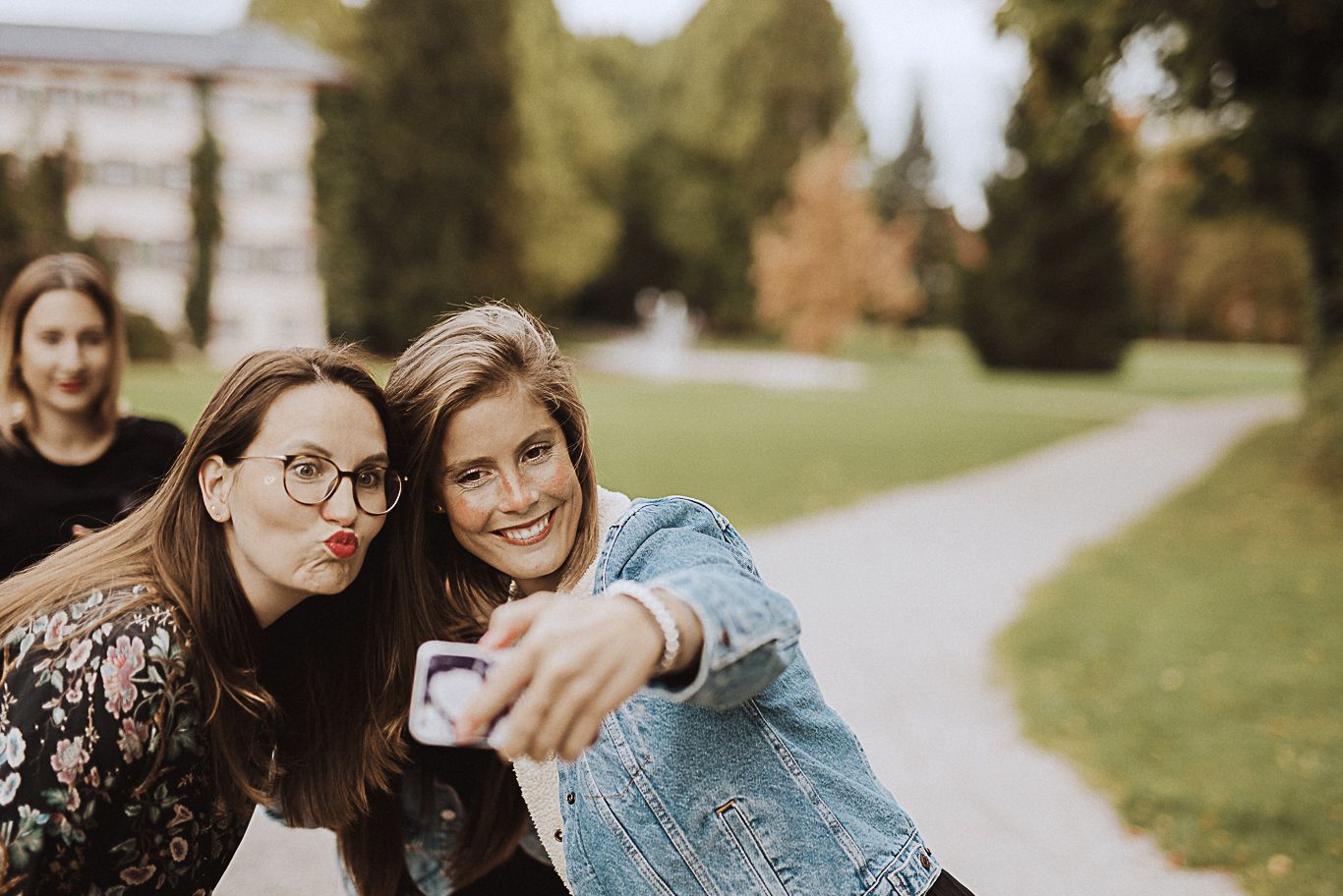 Zwei Freundinnen machen ein Selfie auf einem Weg im Park
