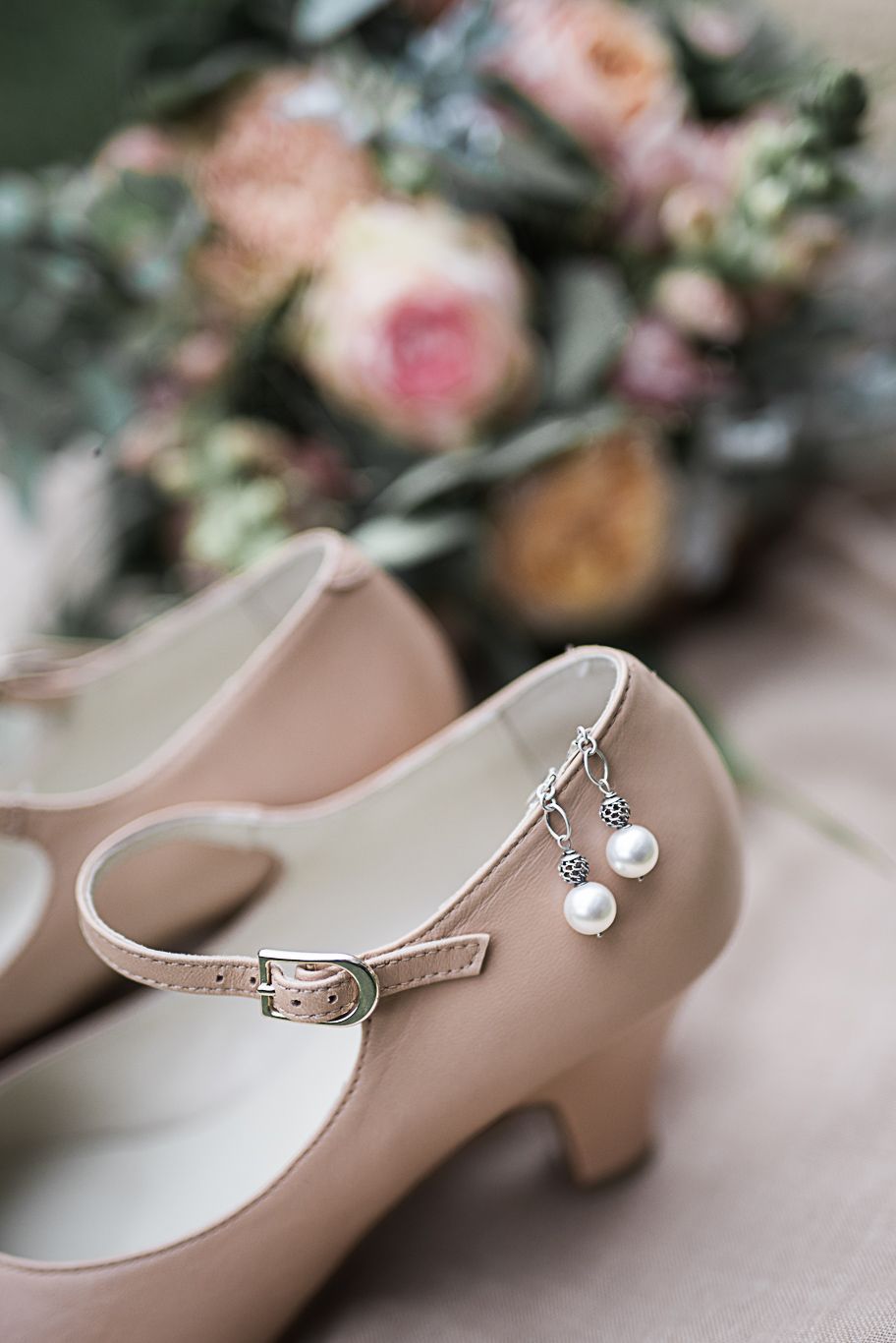 Brautschuhe mit Perlenschnalle stehen neben dem Brautstrauß