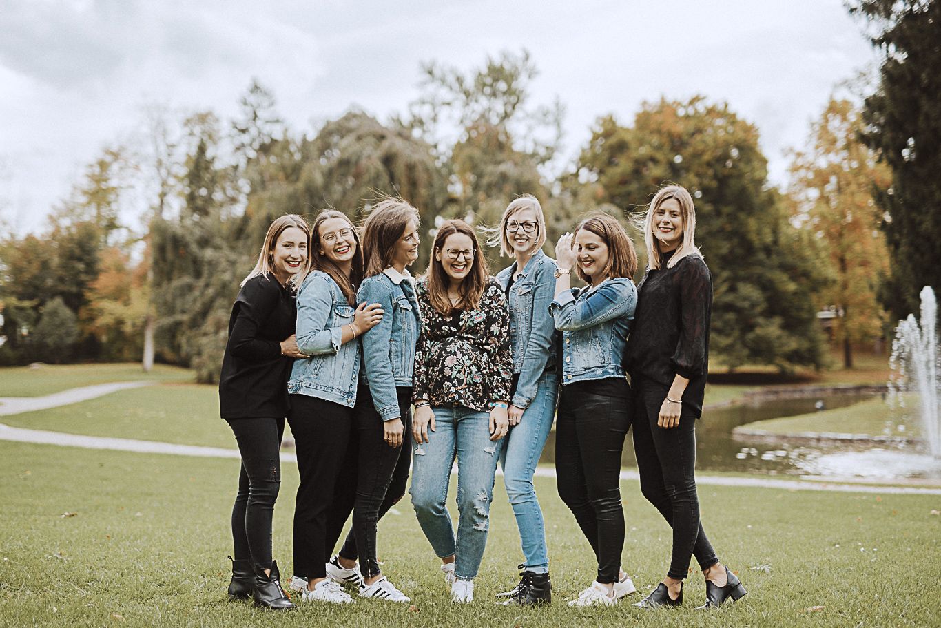 Gruppe Frauen umarmt sich lachend im Park