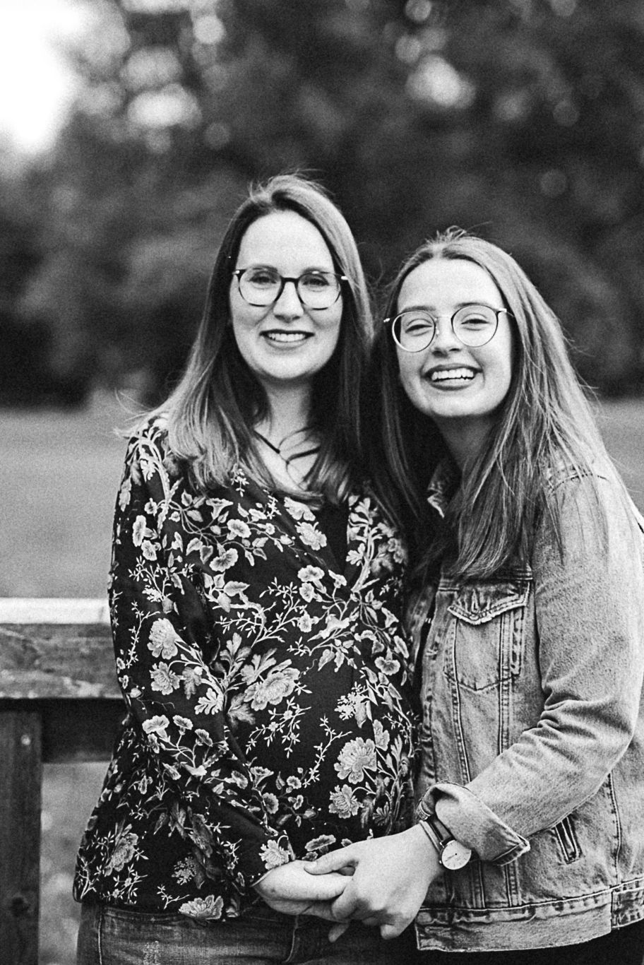 Zwei Frauen mit Brille stehen lächelnd nebeneinander, Schwarzweißaufnahme