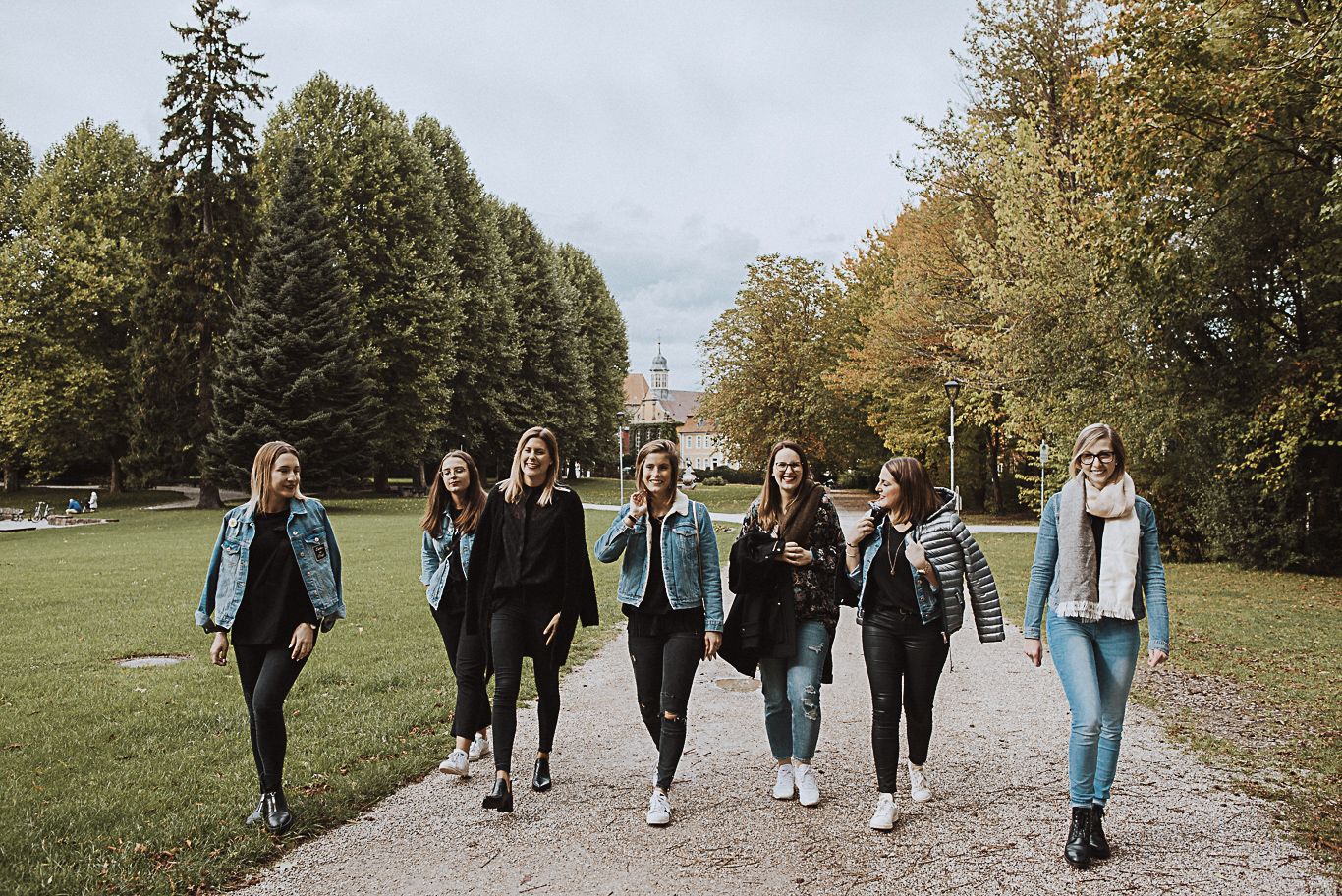 Gruppe Frauen geht lachend über einen herbstlichen Weg