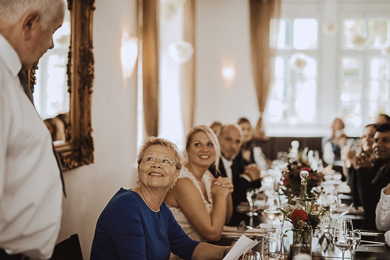 Gäste sitzen lachend an der festlich gedeckten Tafel