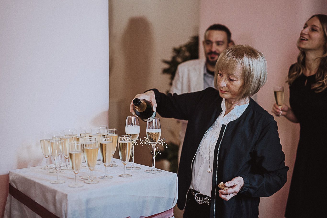 Frau schenkt Sekt in Gläser auf einem gedeckten Tisch ein