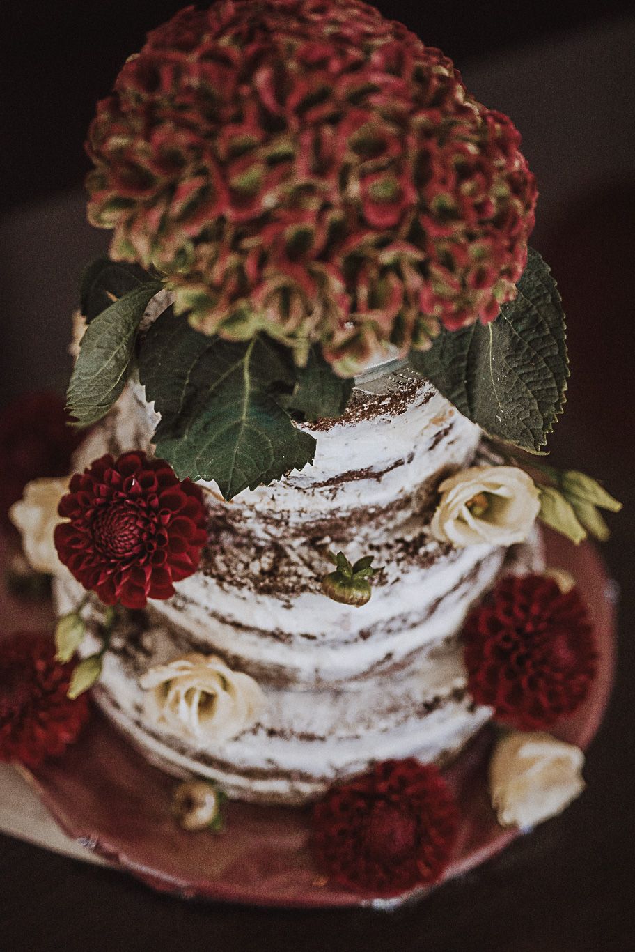 Mehrstöckige Hochzeitstorte mit roten Blüten dekoriert