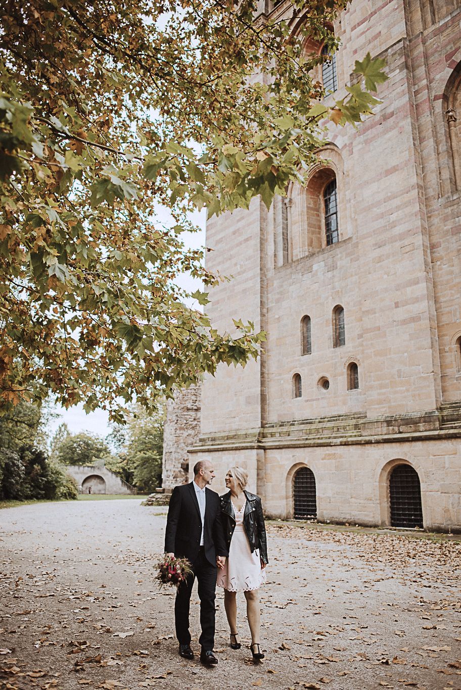 Brautpaar geht an einer historischen Kirche vorbei