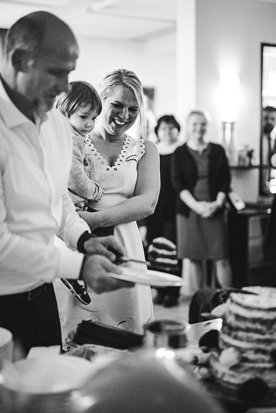 Familie schneidet gemeinsam lächelnd die Hochzeitstorte an