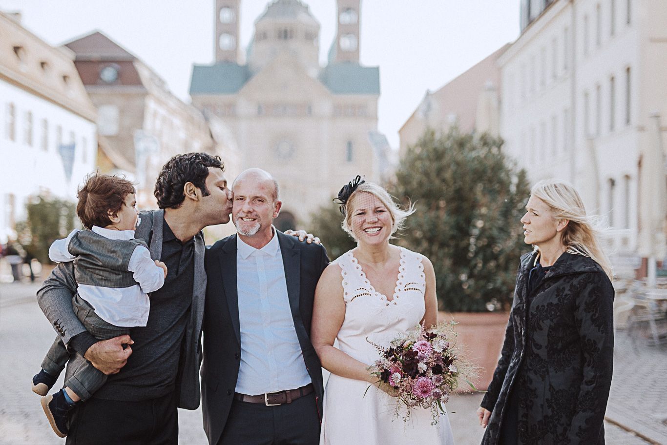 Familie mit Kleinkind lacht gemeinsam auf der Straße