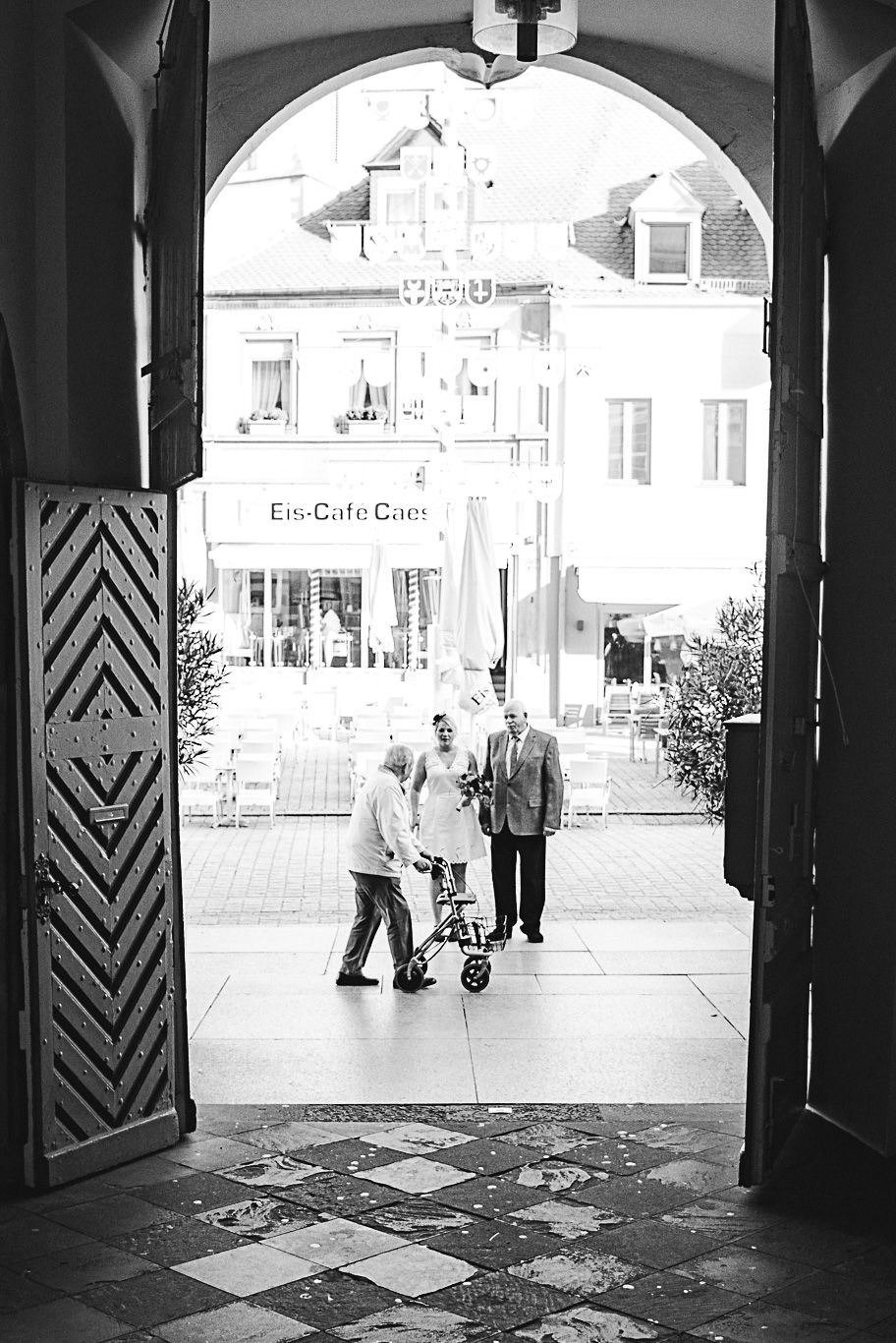 Blick durch offenes Portal auf die Straße mit Passanten, Schwarzweißaufnahme