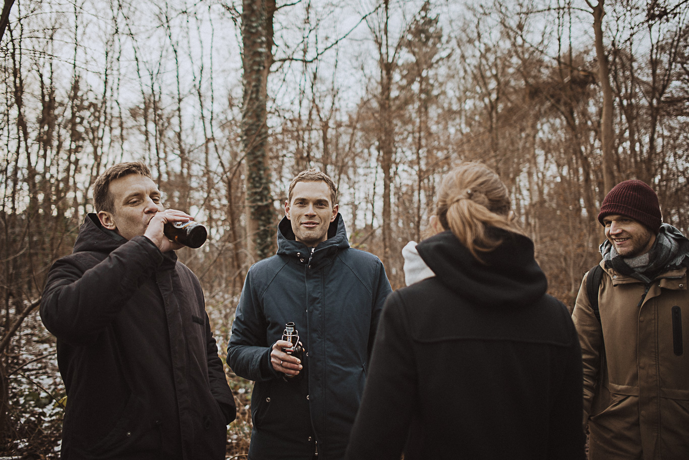 Gäste trinken lachend im winterlichen Wald zusammen