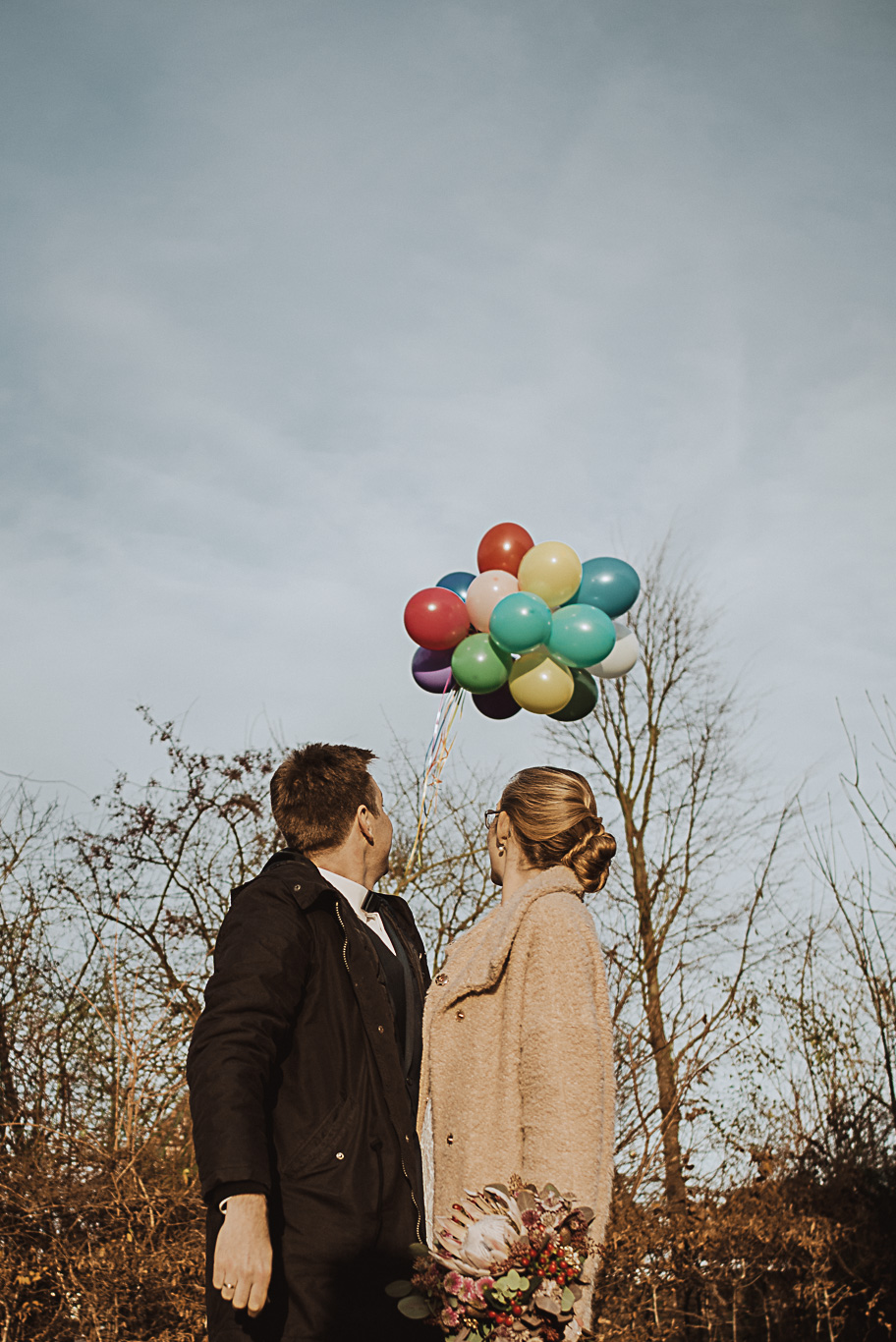 Bräutigam lässt bunte Luftballons vor der Braut in die Höhe
