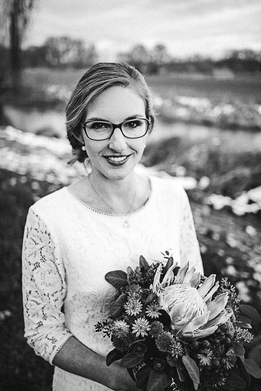 Braut mit Brille hält einen winterlichen Trockenblumenstrauß