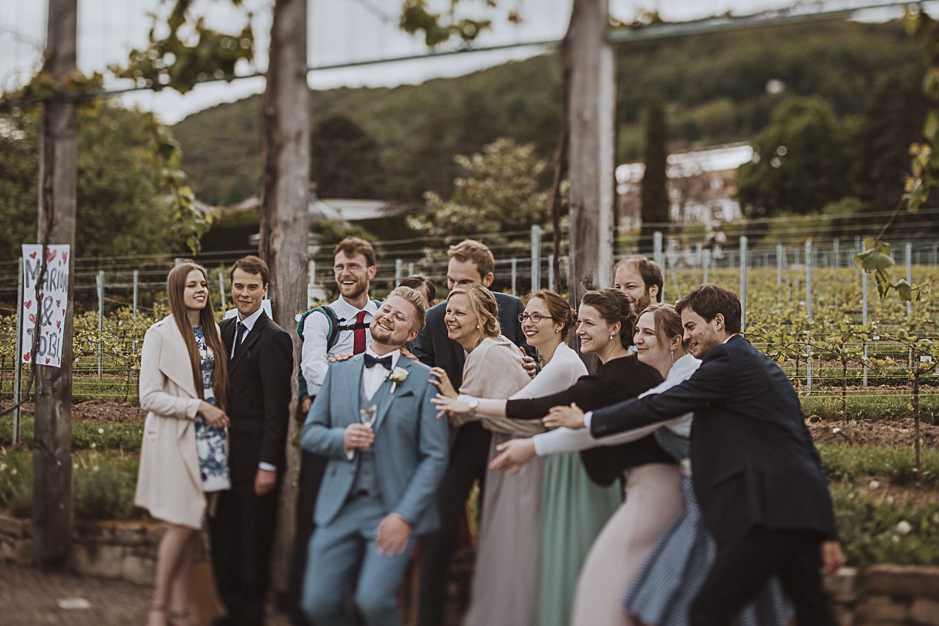 Gäste ziehen sich lachend an den Händen im Weinberg