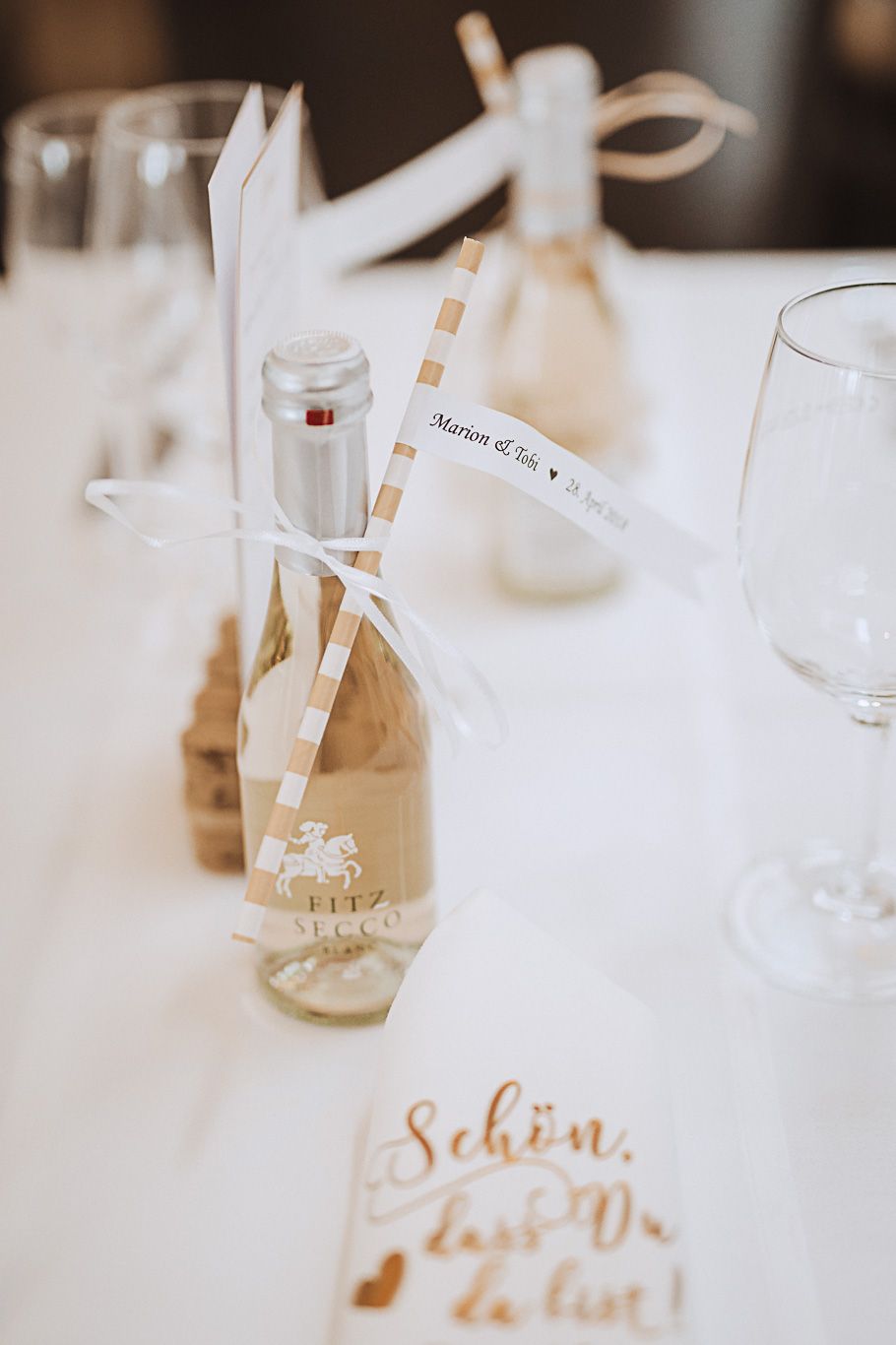 Sektflasche mit Schleife steht auf einem gedeckten Tisch