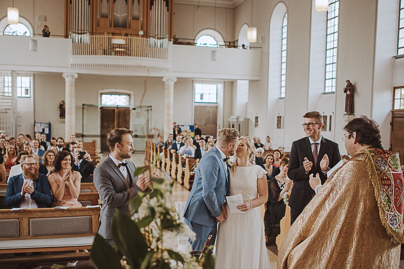 Brautpaar steht mit Pfarrer vor Gästen in der Kirche