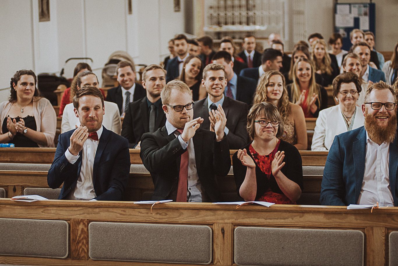 Gäste applaudieren lächelnd in den Kirchenbänken