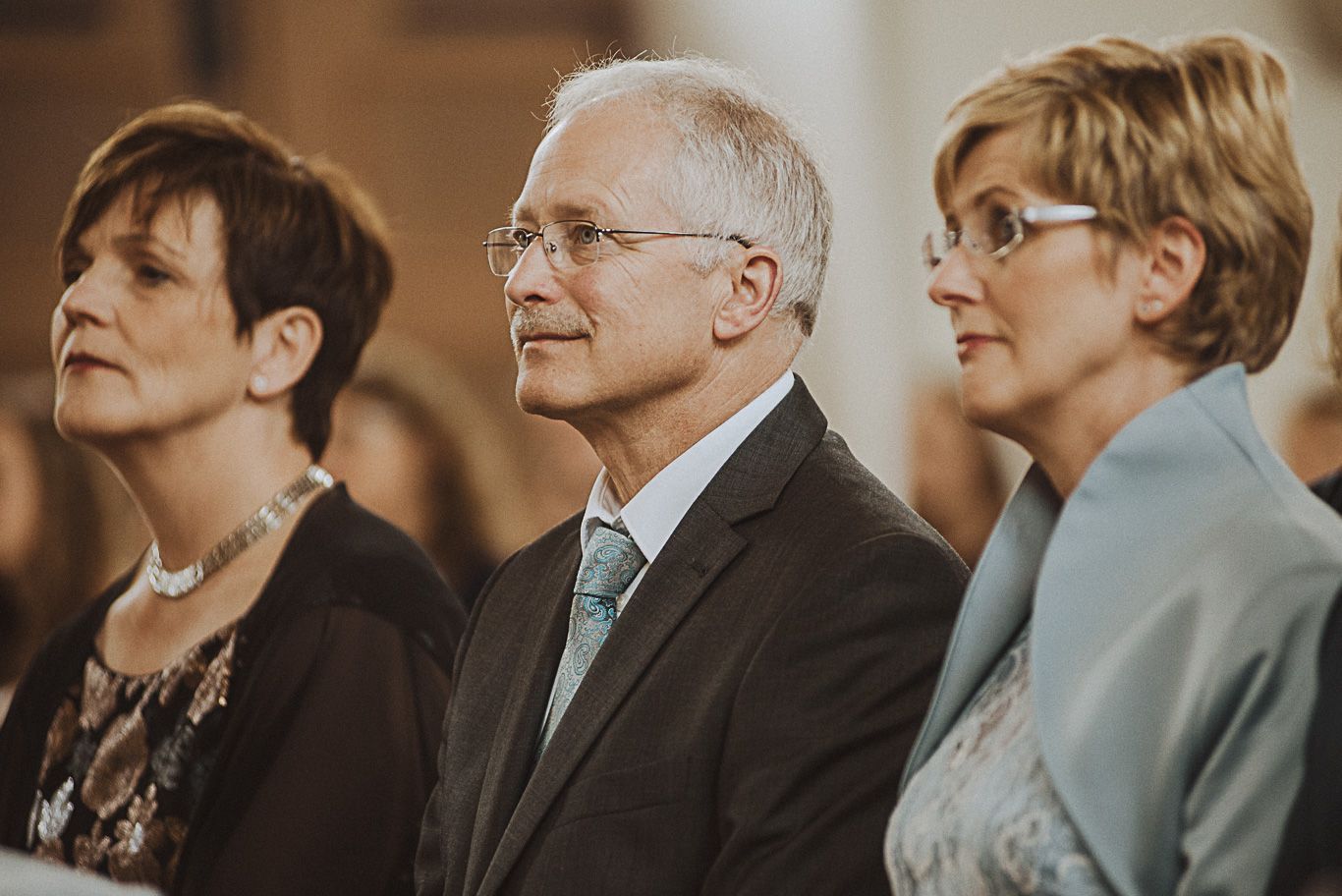Elternpaar sitzt aufmerksam nebeneinander in der Kirchenbank