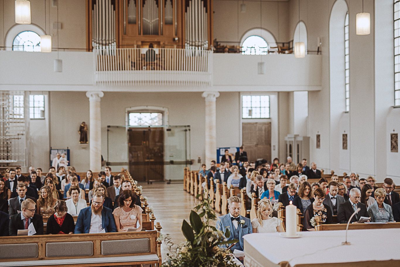 Gäste sitzen während der Trauung in den Bankreihen der Kirche