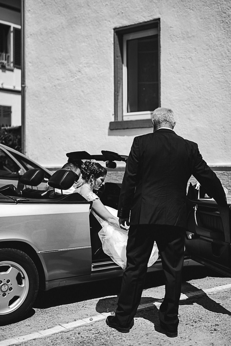 Mann hebt Brautstrauß aus dem Auto, Schwarzweißaufnahme