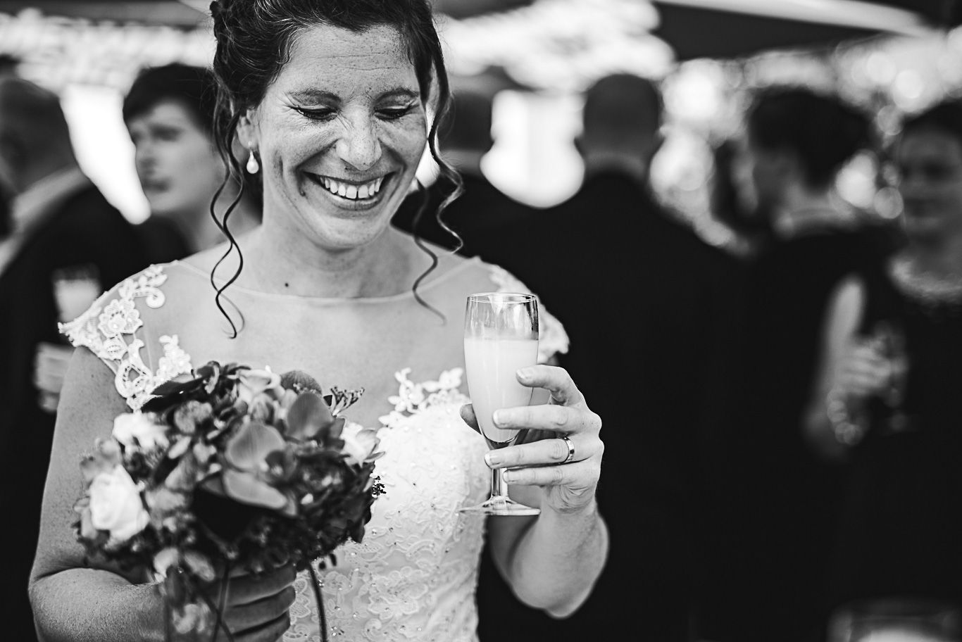 Braut lacht mit einem Glas in der Hand, Schwarzweißaufnahme