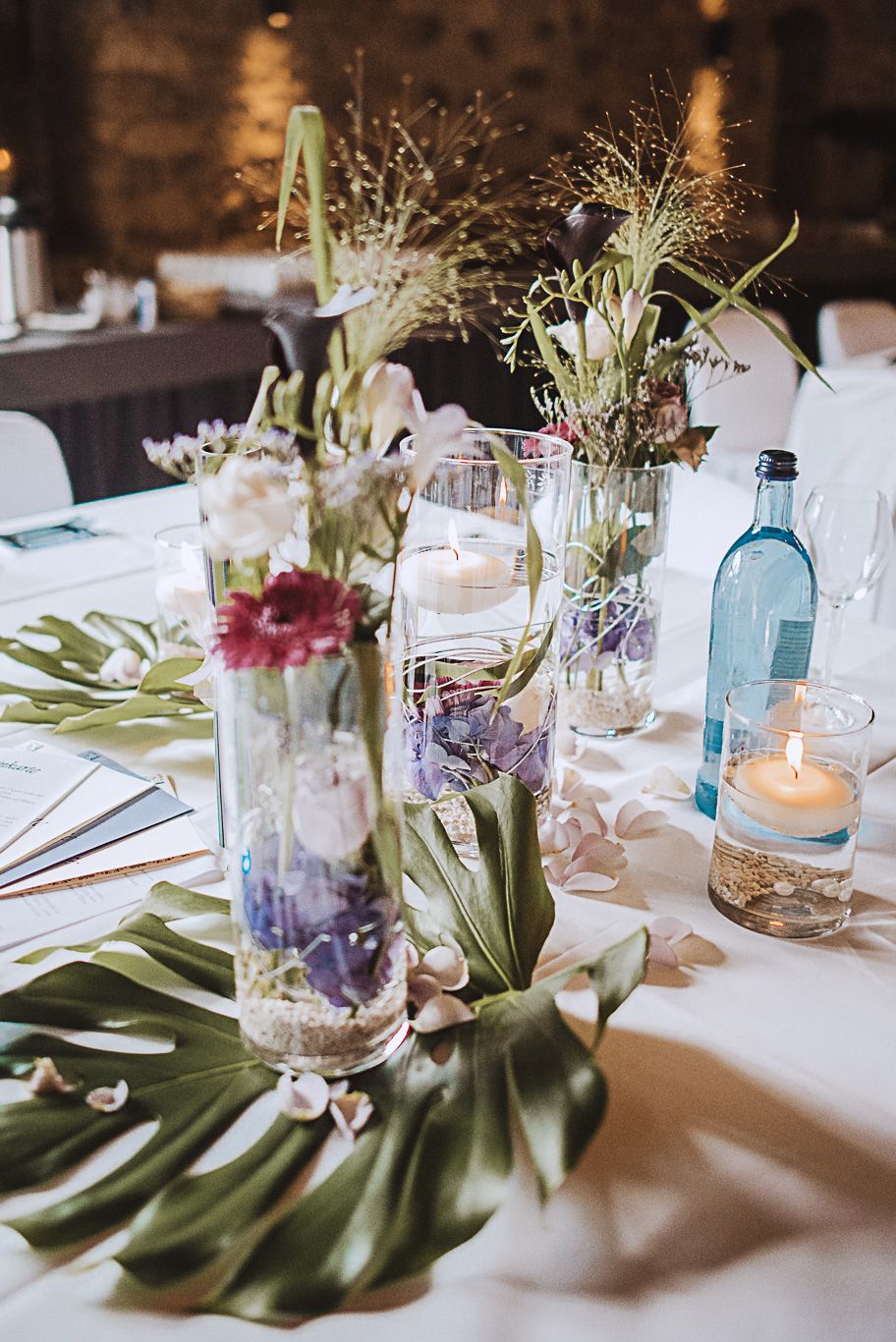 Tischdekoration mit Blumen und Kerzen in Glasvasen