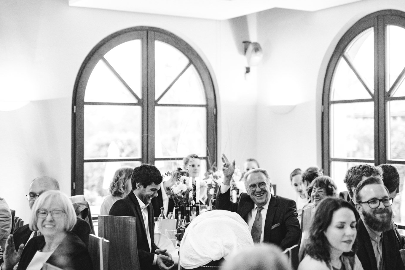 Gäste sitzen gemeinsam an festlich gedecktem Tisch im Saal