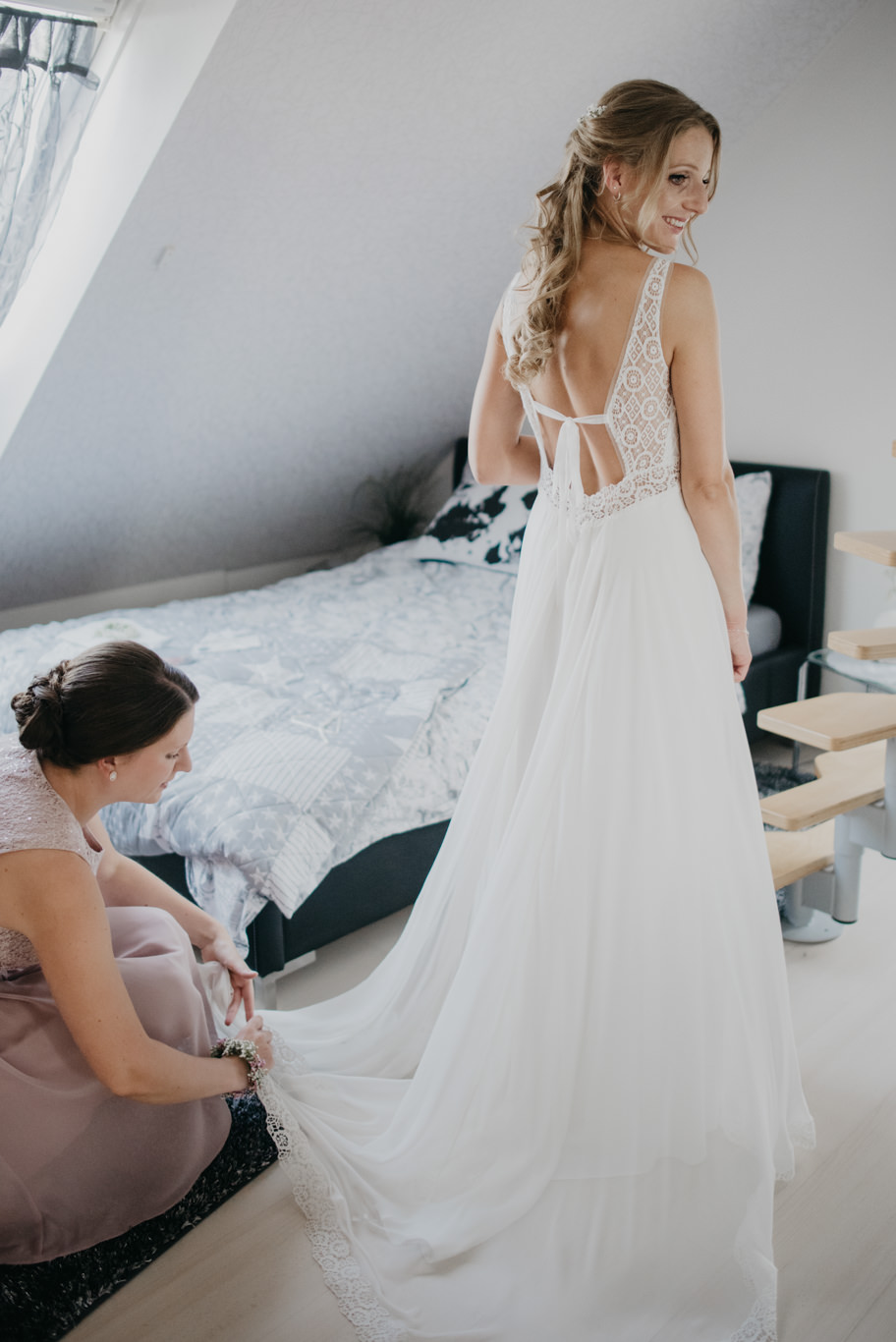 Brautjungfer hilft der Braut in ihr Hochzeitskleid