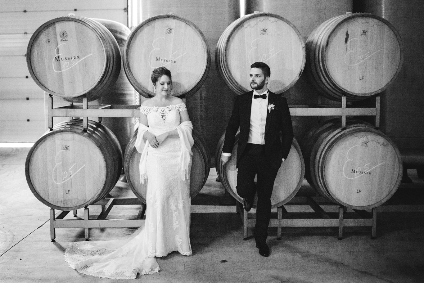 Braut und Bräutigam stehen zwischen Weinfässern im Weingut Mussler