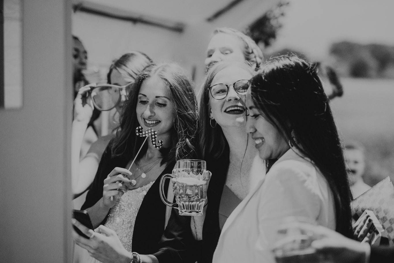 Drei Freundinnen lachen mit Gläsern in der Hand, Schwarzweißaufnahme