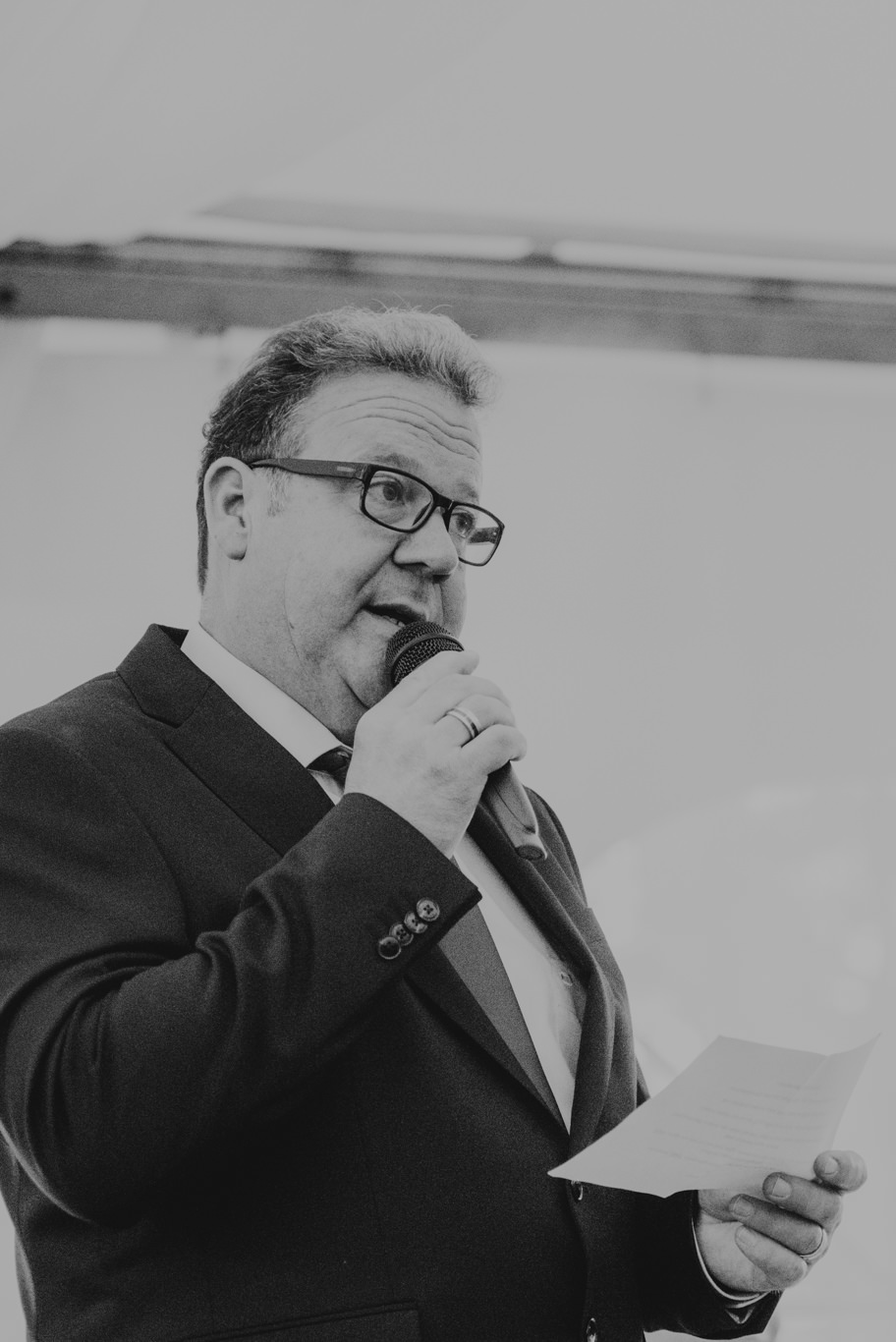 Mann hält lächelnd eine Rede mit Mikrofon