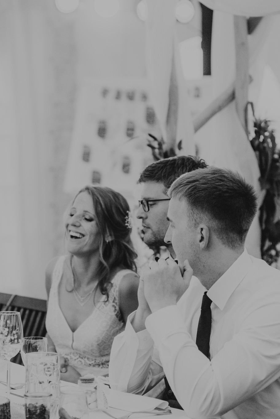 Schwarzweißaufnahme, Gäste lachen bei einer Rede am Tisch