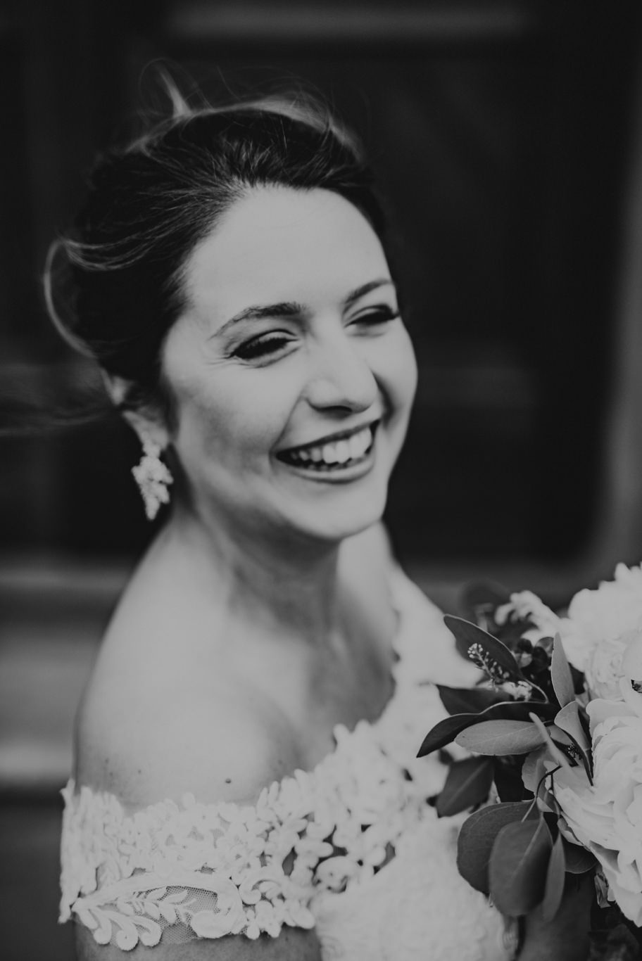 Braut mit Blumen im Haar lacht über die Schulter, Schwarzweißaufnahme