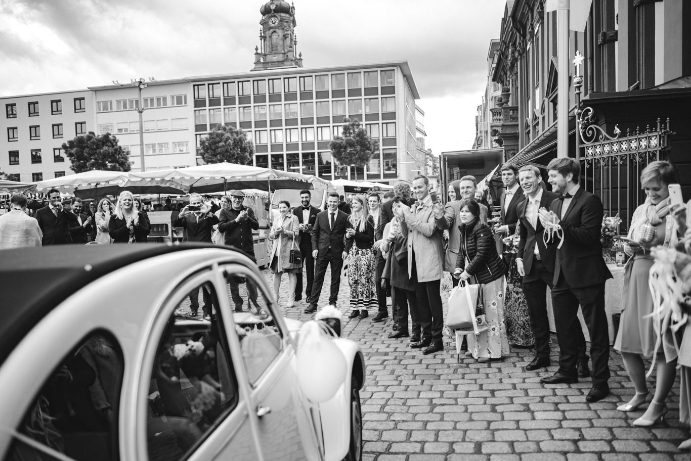 Schwarzweißaufnahme von Hochzeitsgästen, die sich vor historischem Gebäude versammeln