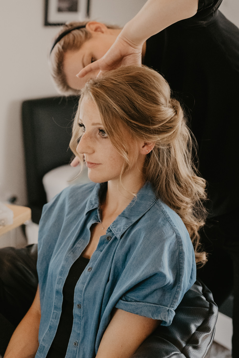 Friseurin stylt das Haar der Braut im Seitenprofil