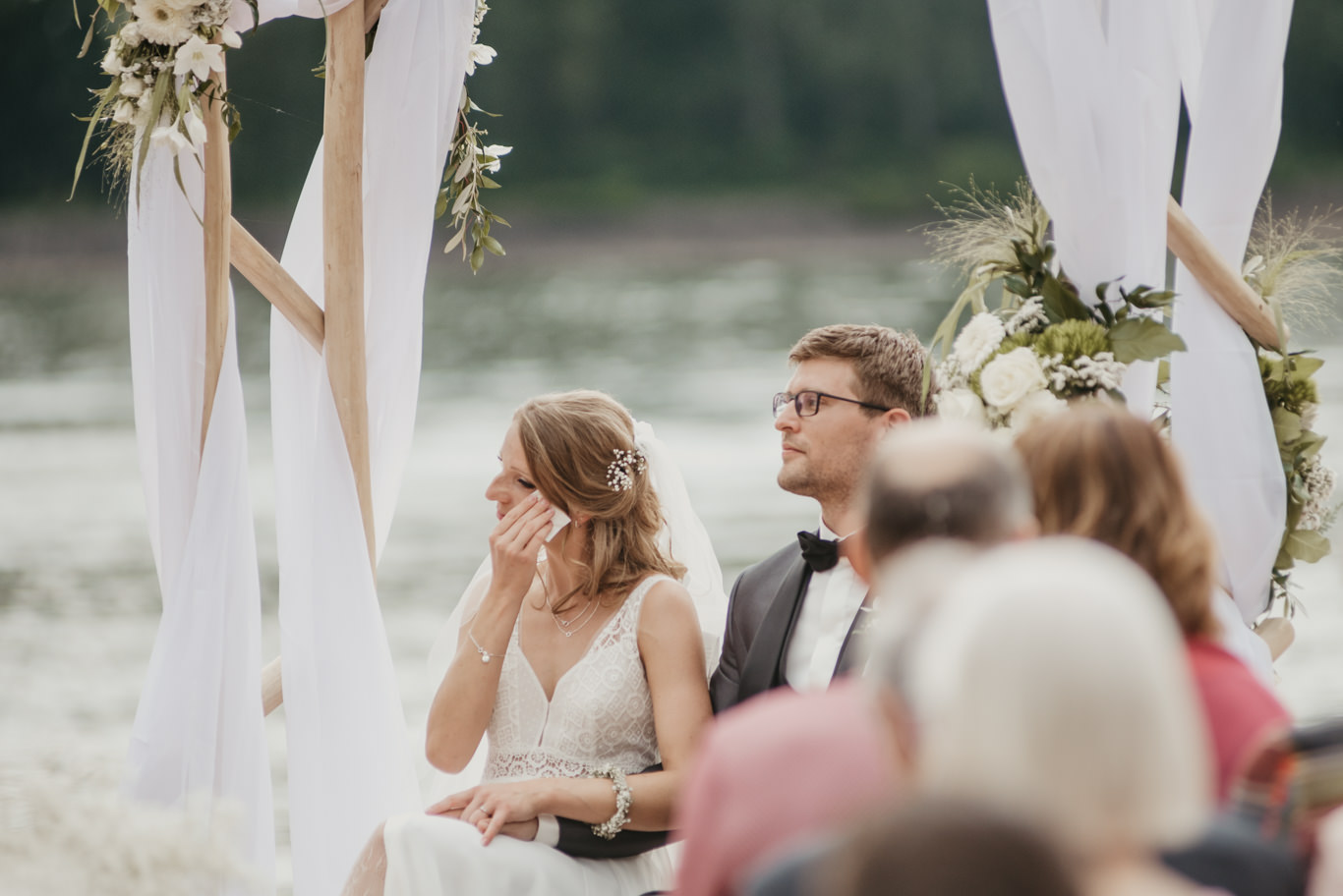 Braut wischt sich gerührt eine Träne bei der Zeremonie am Wasser weg